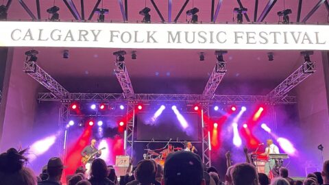 Festival audience facing a brightly lit main stage
