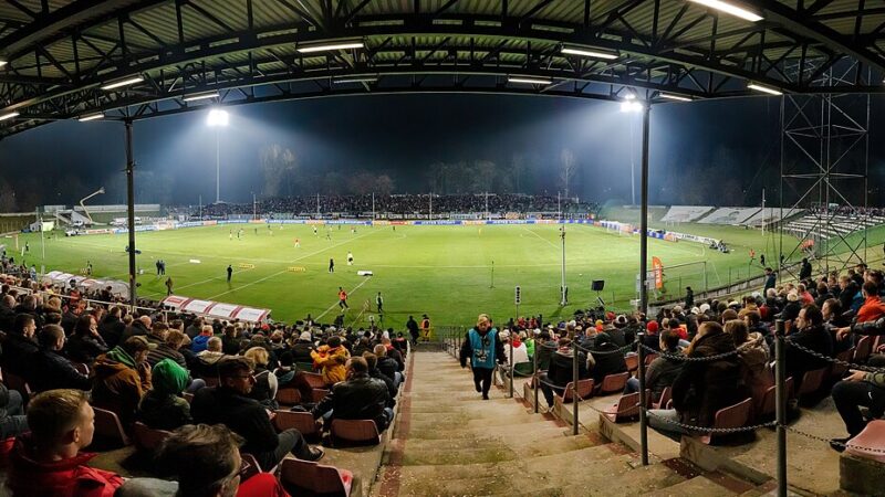 Stadium under floodlights at night with crowd