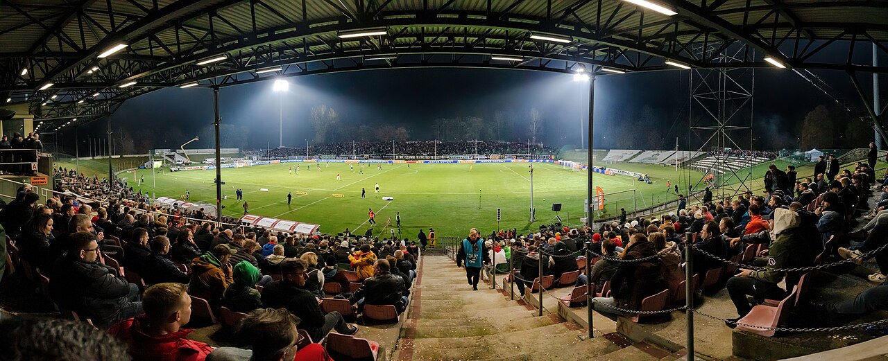 Stadium under floodlights at night with crowd