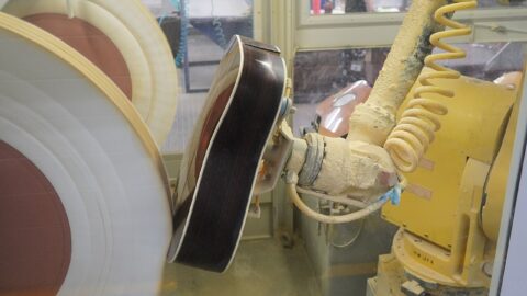 Industrial robotic arm polishing guitars in a factory