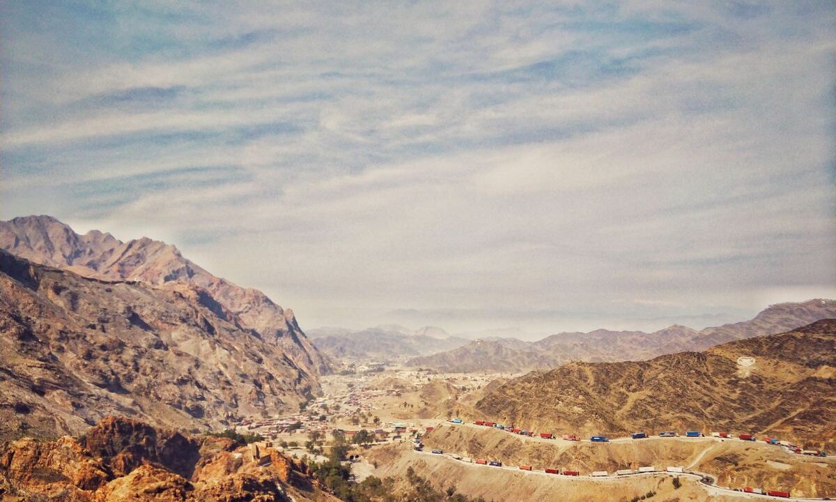 Mountain valley road with truck convoys near the Torkham border crossing