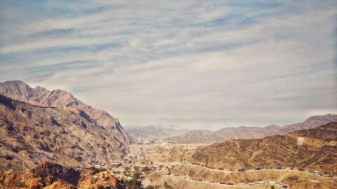 Mountain valley road with truck convoys near the Torkham border crossing